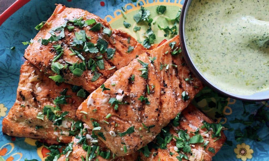 This is the absolute best grilled marinated salmon ever! Served with a side of green herby sauce and sprinkled with cilantro, it is sure to be a crowd pleaser.