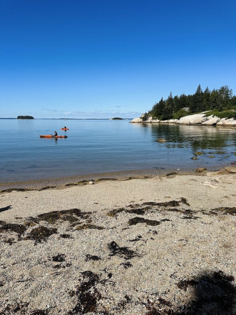 Two kayakers enjoy the cove at Sand Beach on a calm and sunny day.