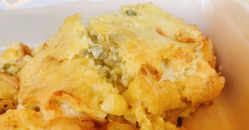 Beautiful corn casserole is set on the table in a dutch oven ready for serving.