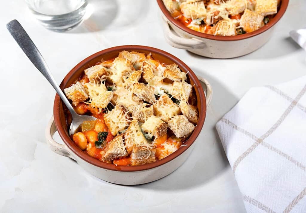 Cheesy Tuscan Kale and Bean soup is topped with croutons and cheese for comfort in a bowl!
