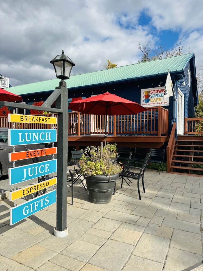 The bright cheery sign and vibrant blue exterior with red umbrellas of Stowe Street Cafe make the space very inviting.