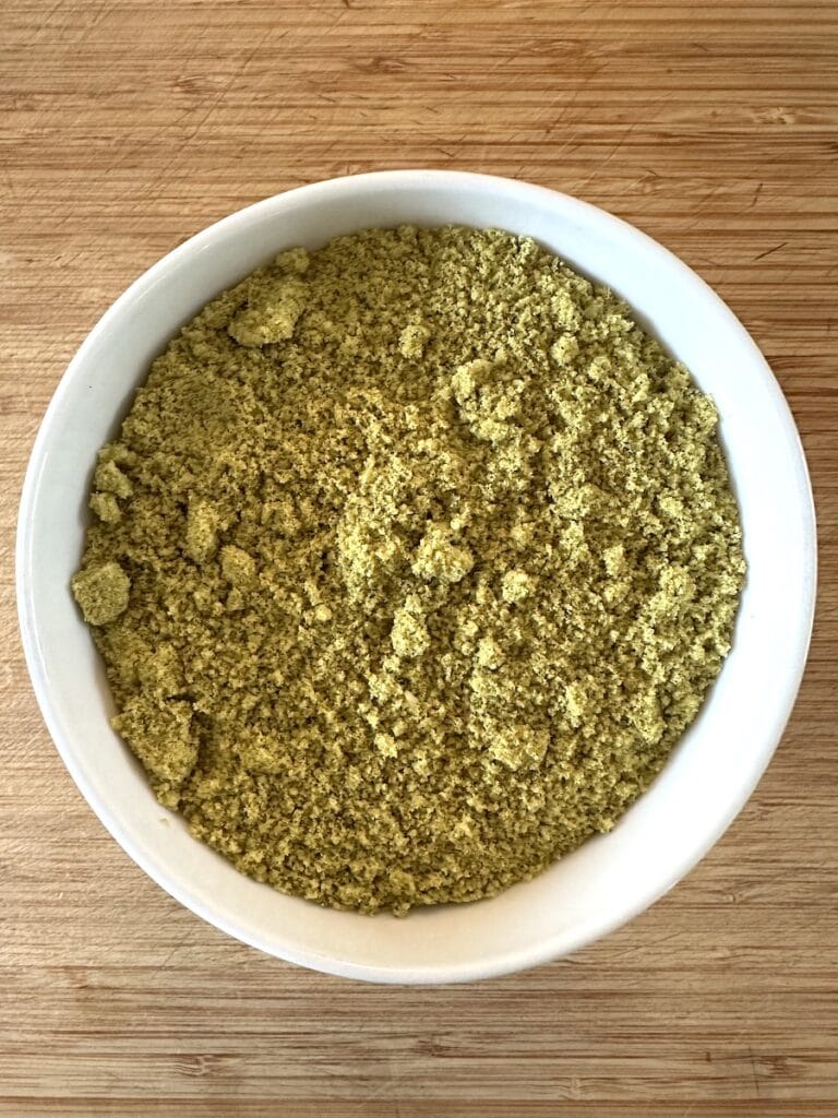 A close up of powdered hummus or instant hummus in a white bowl on a bamboo counter.