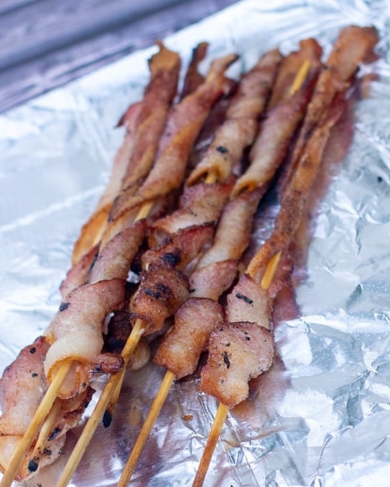 Kabob sticks are used to wrap bacon and hold them in place while cooking over the campfire. They are one of the most unique camping food ideas!