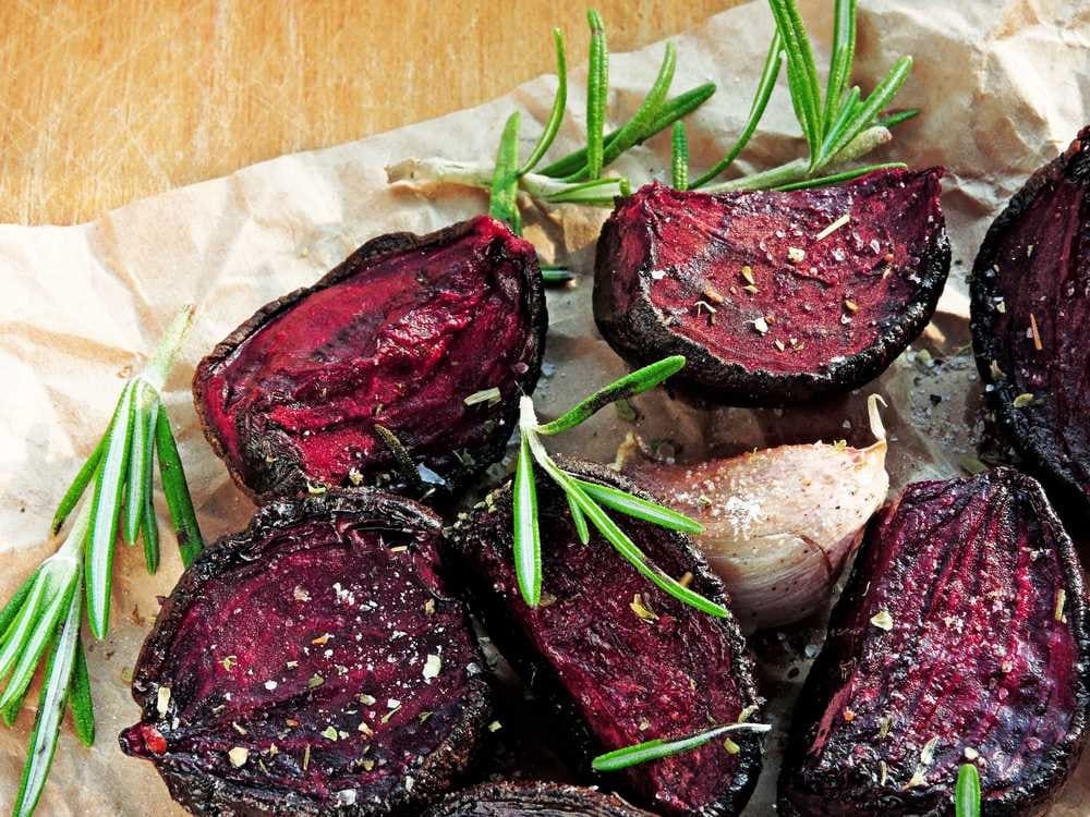 Grilled beets set on parchment paper with a garnish of rosemary look deliciously flavorful.