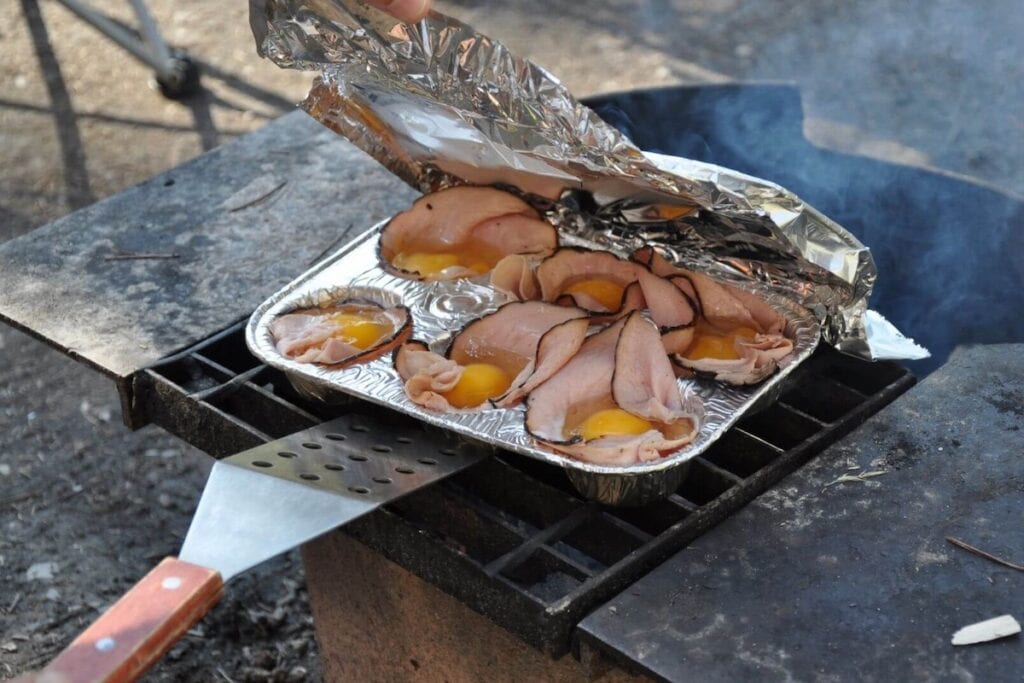 Campfire egg cups are a fun camping food idea for breakfast. Ham is used as the muffin cup.