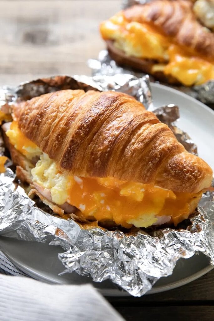 A scrumptious croissant breakfast sandwich oozes with cheese, a delightful and make-ahead choice for a satisfying camping morning.