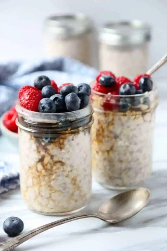 A close-up of a mason jar filled with delicious overnight oats with berries, a convenient camping breakfast.
