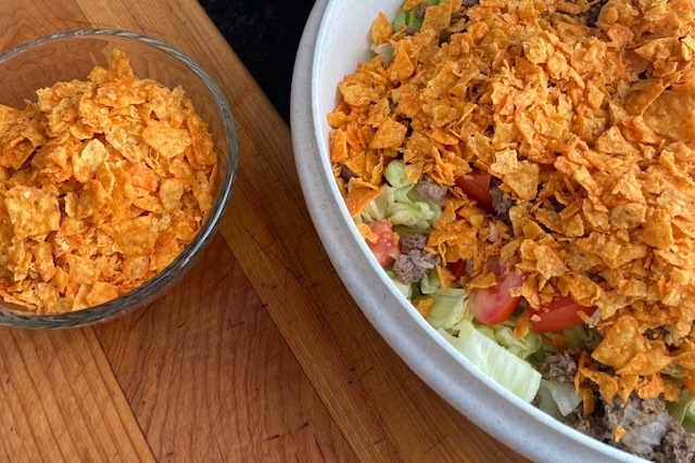 This taco salad recipe uses nacho cheese chips such as Doritos. They add a crispy crunch to the tossed salad.