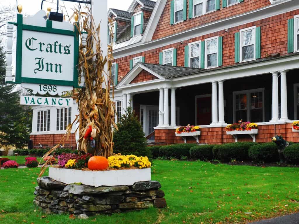 Crafts Inn in Wilmington, Vermont is decorated for the fall with pumpkins and dried corn stalks. It's brown shingled siding and green shutters have a quaint appearance.
