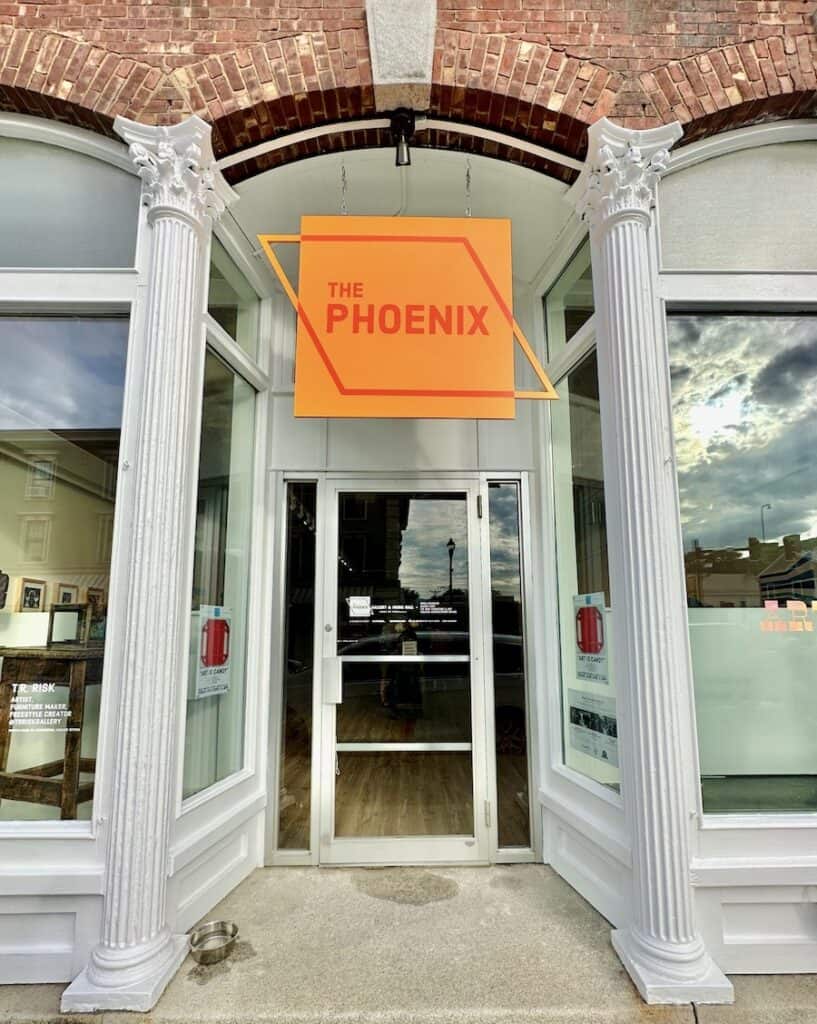 The Phoenix Gallery has a bright orange sign and classic white columns welcoming visitors inside to view the art on display.