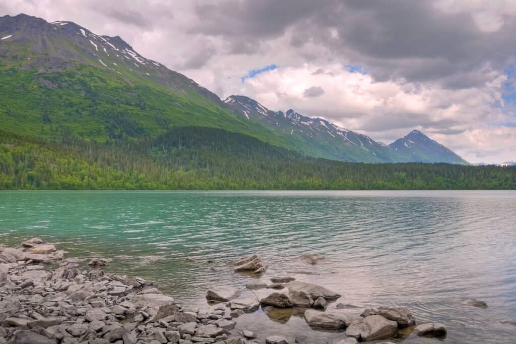 A view of crystsl clear Johnson Pass and Upper Trail Lake. The clouds cover most of the blue sky.
