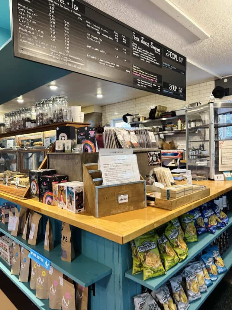 The inside of Stowe Street Cafe is cheery with a turquoise display case at the cashier counter and fun gifts to purchase thoughtfully scattered throughout the store. The black menu board hangs above the counter.
