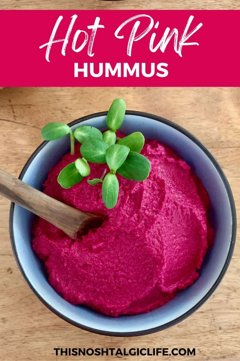 A promotional image showing a blue bowl with hot pink hummus and green pea shoots sitting on a wooden surface. The text reads "hot pink hummus" and at the bottom is "thisnoshtalgiclife.com".